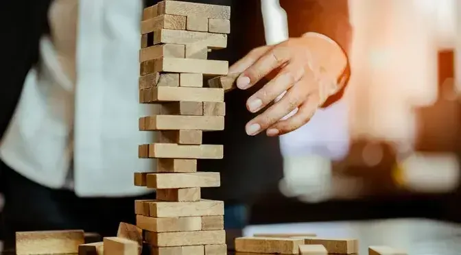 A businessman trying to balance moving wooden pieces, like chasing fat through a process